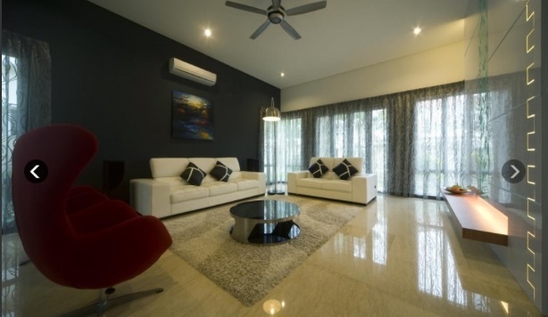 This elegant living room, designed by Inventive Design Firm Sdn. Bhd. for Manja Villa @ Menjalara, showcases a modern aesthetic with clean lines. The space features a striking red accent chair, a plush white sofa set, and a sleek black wall that contrasts beautifully against the polished marble flooring. Delicate sheer curtains allow natural light to accentuate the minimalist décor, highlighting the firm's commitment to creating sophisticated and welcoming interiors for their discerning clientele.