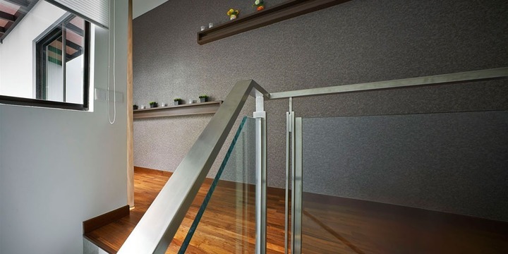 A sleek staircase landing in a South Bay Residence, Penang, exudes contemporary elegance by Archiplan Interior Design. The space features a rich wooden floor, a textured gray wall accent, and a minimalist glass railing, with subtle decor on a floating shelf. The simplicity and modernity resonate with the album's theme, appealing to those seeking modern interior inspiration with a touch of sophistication.