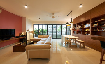 This image showcases a modern contemporary living room by Expression Design & Contract Sdn. Bhd., featuring a warm palette with a striking coral accent wall. The room boasts sleek furnishings, including a cream sectional sofa, a wooden bookcase, and a simplistic dining set, all under ambient ceiling lighting. The polished floor gleams, complementing the natural light flowing in from the balcony of this G Residen project, accentuating the seamless blend of comfort and chic design.